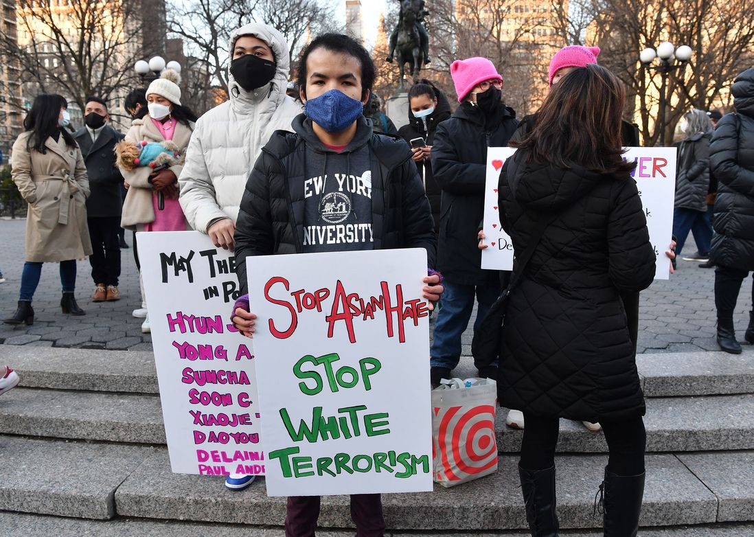 People carry signs, including one of all the victims' names and another that says "Stop Asian Hate. Stop White Terrorism."